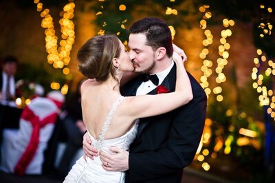 Couple kissing while dancing at Margaret Place wedding with glowing lights in the background
