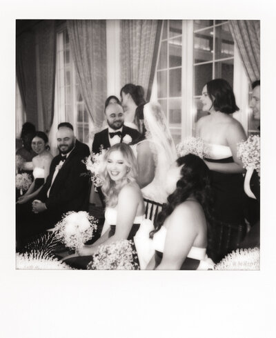 Polaroid photo of a newlywed couple kissing at dusk in a field, wearing playful wedding attire — a dreamy image captured by a film wedding photographer.