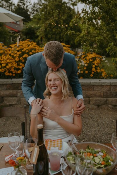 groom leaning over bride and giving her a kiss at their vineyard wedding
