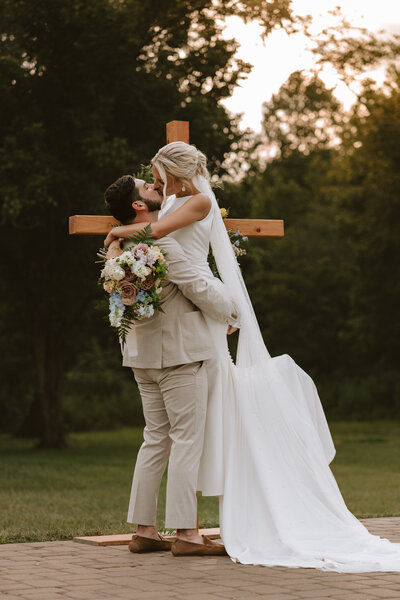 couple kissing in front of cross