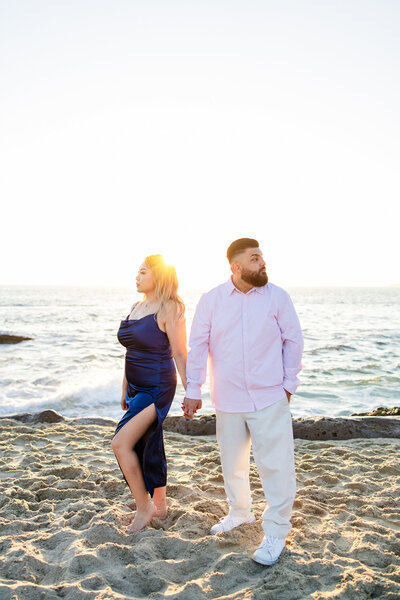 engaged couple holds hands on the beach