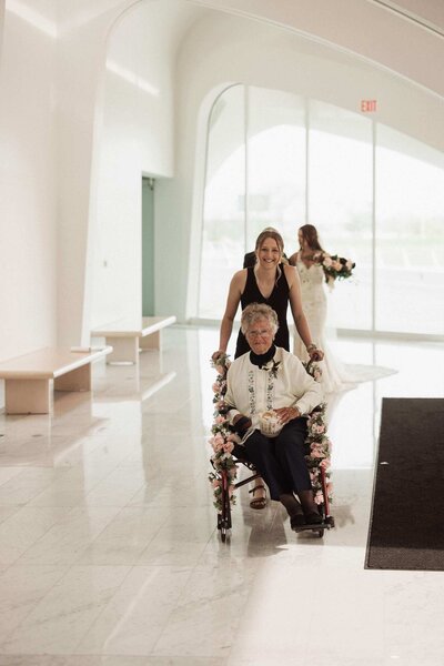 Liz Wisconsin Wedding Planner at The Milwaukee Art Museum pushing flower grandma down  the aisle.