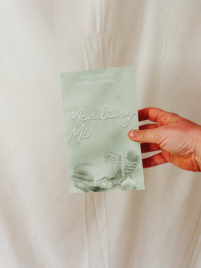 Woman holding copy of Mending me by Rebecca Wrights