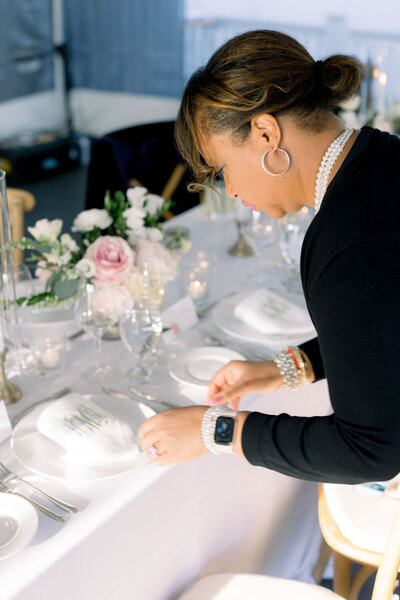 Woman setting up a table for a wedding reception with floral decor