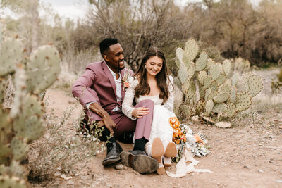 bride and groom sitting in cacti