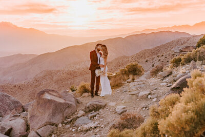 bride and groom kissing on mountain side