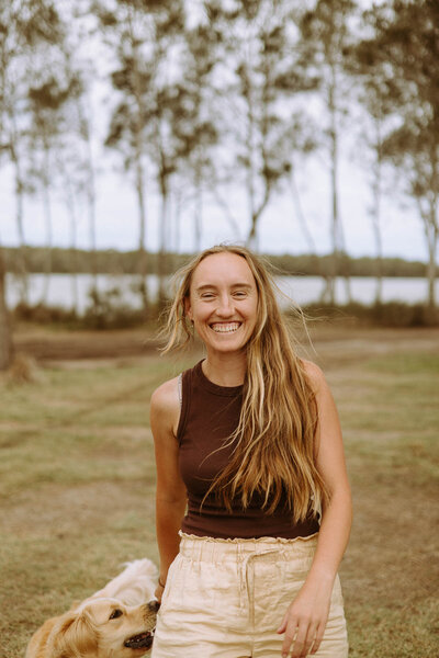 image of photographer with long blonde hair in nature. her golden retriever is behind her.