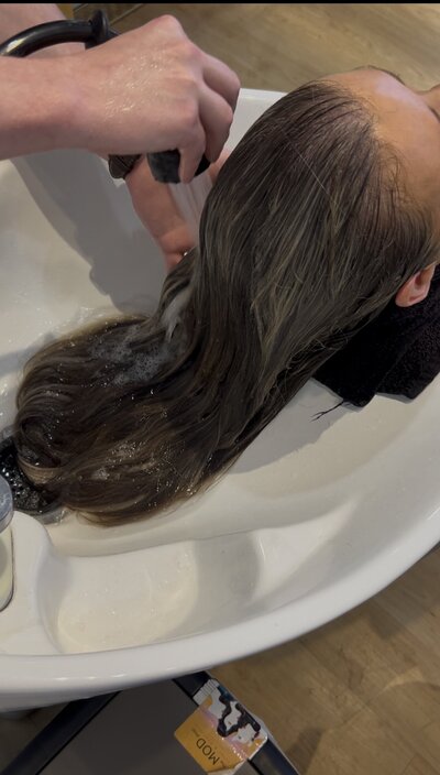 Closeup of a hairdresser washing a woman's hair in a shampoo bowl