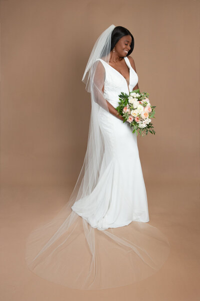 bride wearing a long chapel length veil with blusher and holding a bouquet