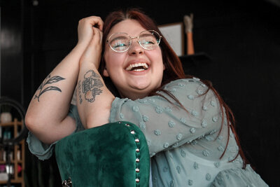 A girl with glasses sitting in a green chair