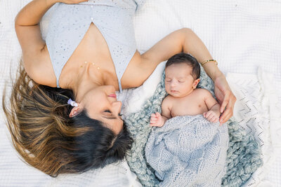 mom and newborn boy laying on bed with props