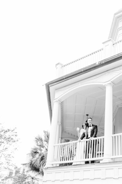 bride and groom waving off of porch at william Aiken house