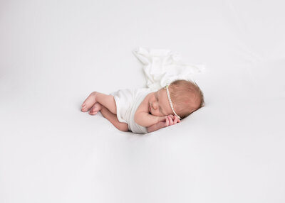 A snuggly newborn girl on white.