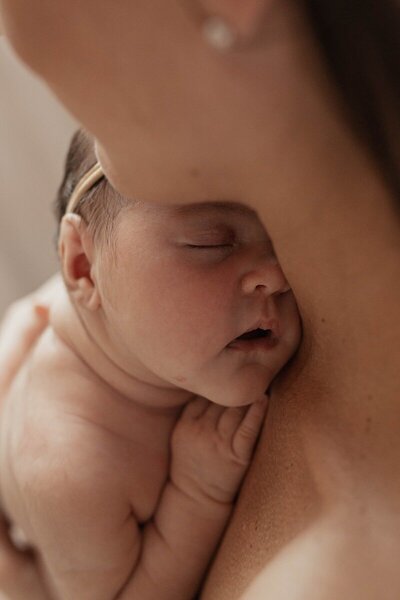 Newborn resting against mother by a photographer in Traverse City

