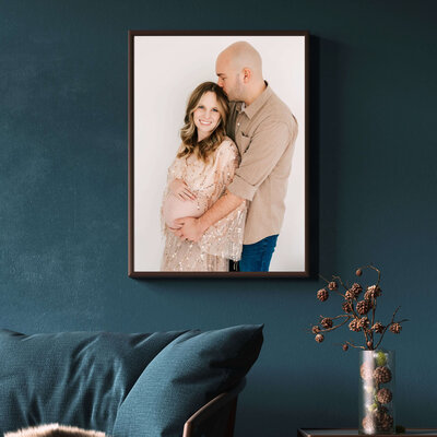 Branson maternity photographer captures framed photo of pregnant couple cuddling on blue wall over couch