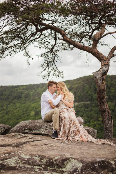 couple sitting on rock in Smoky Mountains during outdoor engagement session