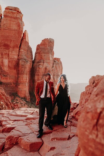 Couple walk along cliff in sedona for their engagement photos