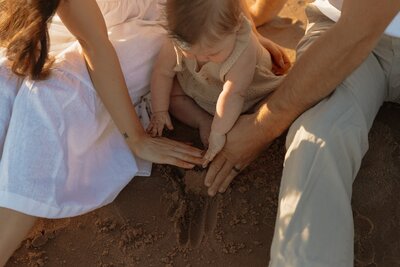 mom and dad posing with toddler on beach for lifestyle portraits