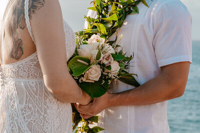A couple holding hands while promising their marriage together forever all while standing on a cliff in Maui with one of our all inclusive packages