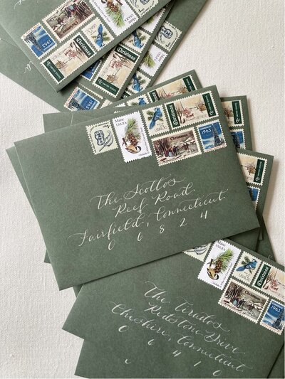 Green Christmas card envelopes with silver ink calligraphy and  holiday theme vintage postage stamps