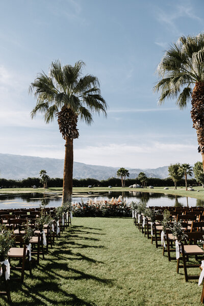Ceremony set up in front of a pond sunny day with palm trees