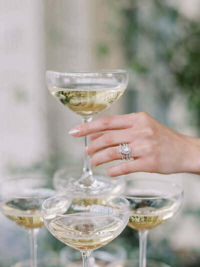 Bride with a luxury wedding ring reaching for champagne tower