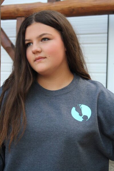 Child wearing Crewneck Sweatshirt, exclusive merch from Spirit’s Respite Ranch that helps support programs and animal care.