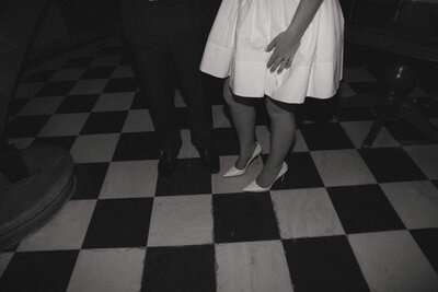 bride and groom standing next to each other on black and white tiled floor