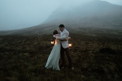 Couple dance with lanterns at blue hour at the Isle of Skye's magical Fairy Pools, Scotland