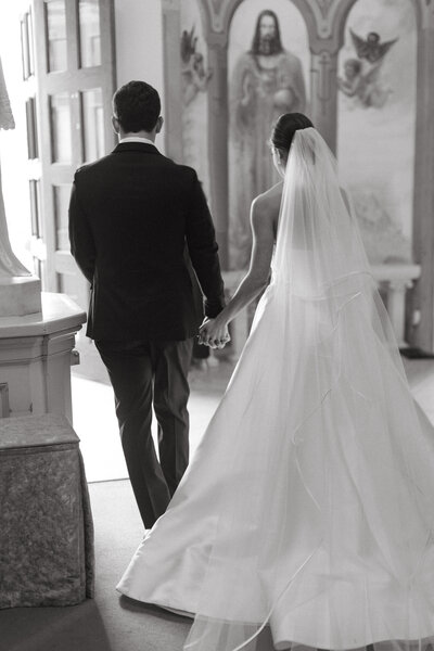 bride and groom hold hands while leaving wedding venue