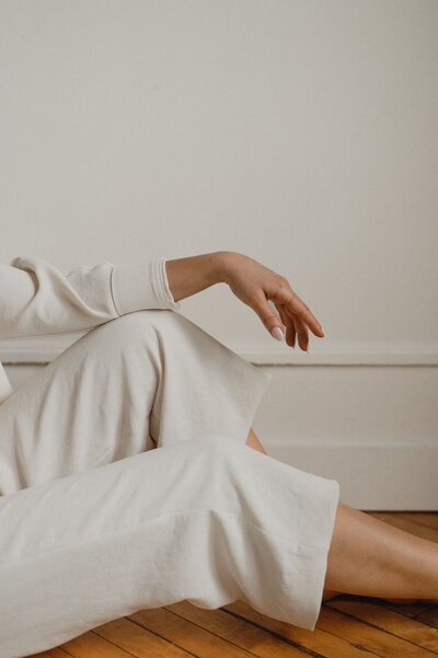 Close-up of a woman’s hand resting on her knee in soft, neutral tones, symbolizing a confident and grounded approach to web design
