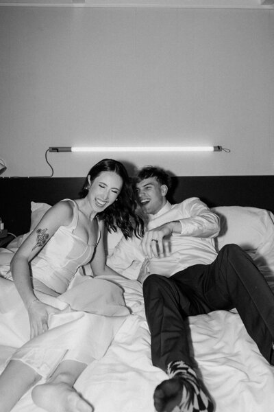 newlyweds laughing on bed in hotel