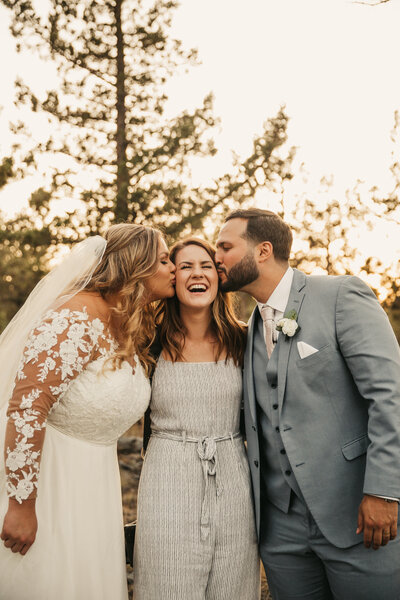 bride and groom kissing photographer's cheeks