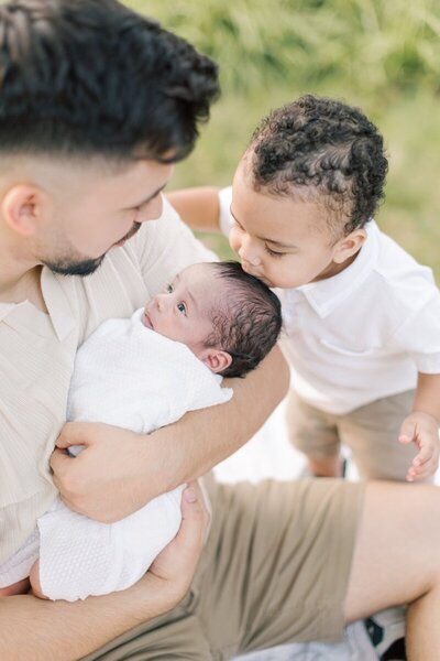 A little boy kisses his newborn brother on the head during NJ newborn photos.
