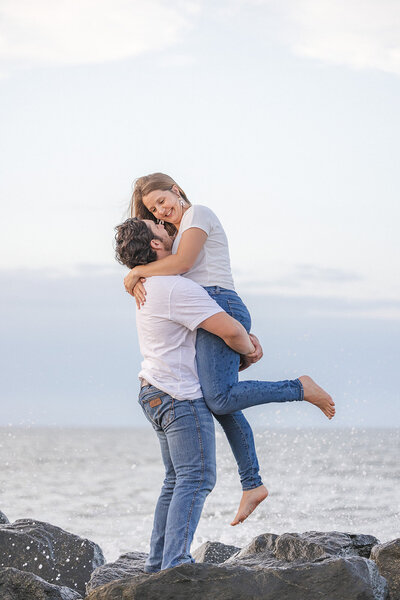 Couple holds each other by the ocean cape henry lighthouse