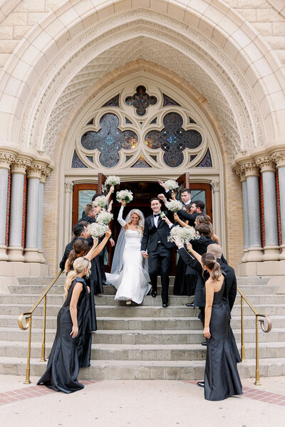 Bride and groom exiting Guadalupe Cathedral in Downtown Dallas with their wedding party cheering by Kortney Boyett Photography, Dallas wedding photographer