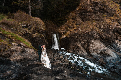 Bride and groom kissing in front of a waterfall along the Oregon Coast