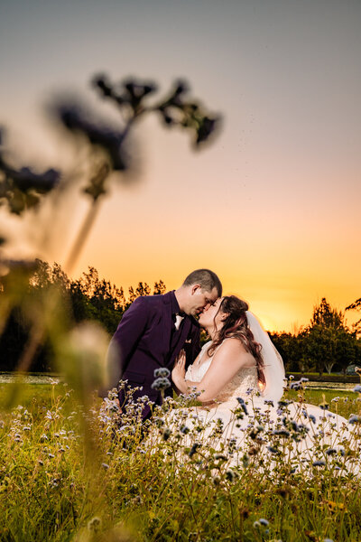 A bride in a white dress stands gracefully on lush green grass, embodying elegance and joy on her special day.