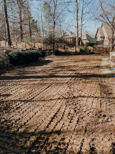 tire-tracks-in-flat-dirt-covered-backyard