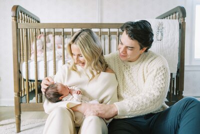 mom and dad smiling at newborn in nursery