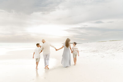 a mother and dad with two sons walking along the beach in Destin Florida