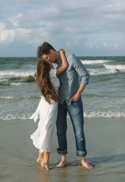 A couple hugging each other and laughing on a beach in Charleston, South Carolina.