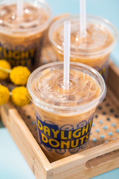 Daylight Donuts Coffee Cup in brown box on blue background - Daylight Donuts