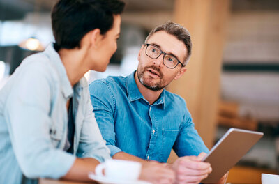 A professional working with a co-worker in an office meeting on monthly ad management, using a laptop as a tool to optimize Google Ads campaigns.