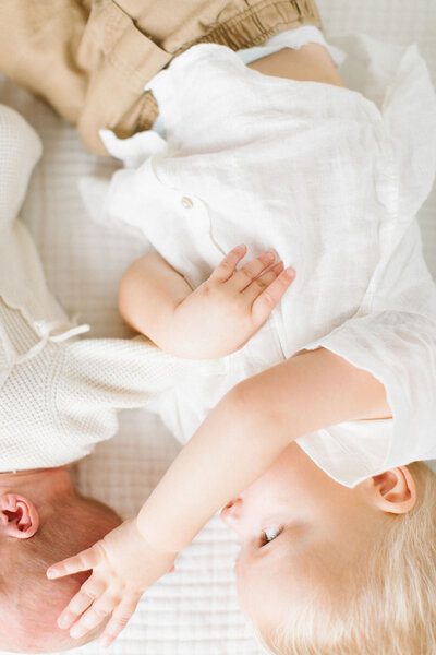 toddler boy sweetly touching his newborn brother's head