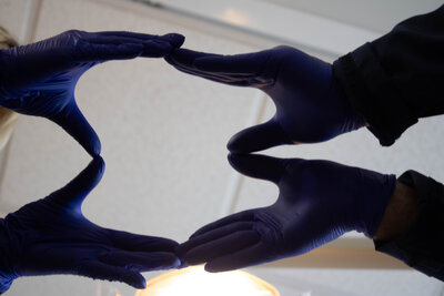 Four hands coming together to form the outline of a tooth. 