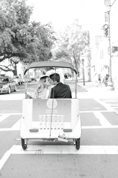 Bride and groom kissing in a pedicab on the street in Charleston South Carolina