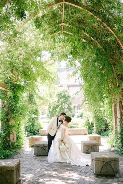Bride & Groom kissing under a pergola on the campus of Notre Dame
