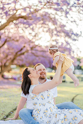 family photos of mum flying baby under jacaranda tree in Brisbane