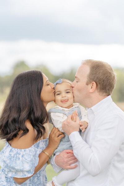 parents kiss baby during family photo in Loudoun County, VA photo